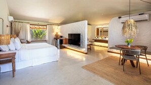 A spacious hotel room with a large bed, a TV, a dining area with a table and chairs, and a small kitchen area. - Reserva Jacumã Boutique Hotel  (Porto Seguro)