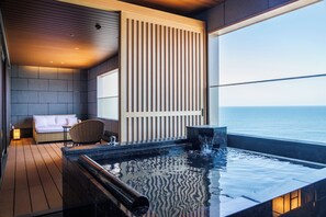 A modern indoor pool area with a view of the sea, a seating area with a sofa and chairs, and a wooden floor. - HOTEL OOSADO (Sado)