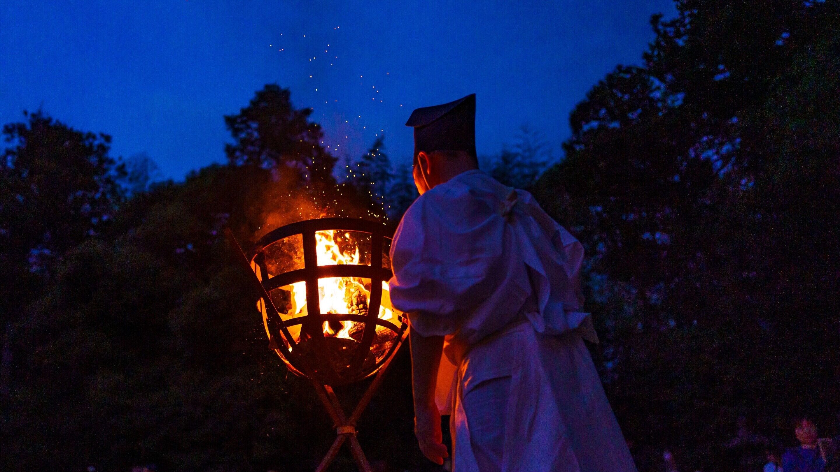 Una persona con toga de graduación sosteniendo un farol encendido.