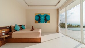 Een slaapkamer met een groot bed, een houten bankje en een schilderij van een olifant aan de muur.