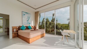 Een moderne slaapkamer met een groot bed, een houten nachtkastje, een witte stoel en uitzicht op bomen door grote glazen deuren.