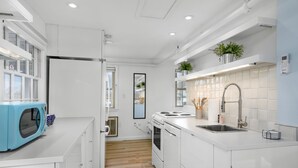 Una cocina moderna con armarios blancos, un microondas integrado, un lavamanos y una estufa.