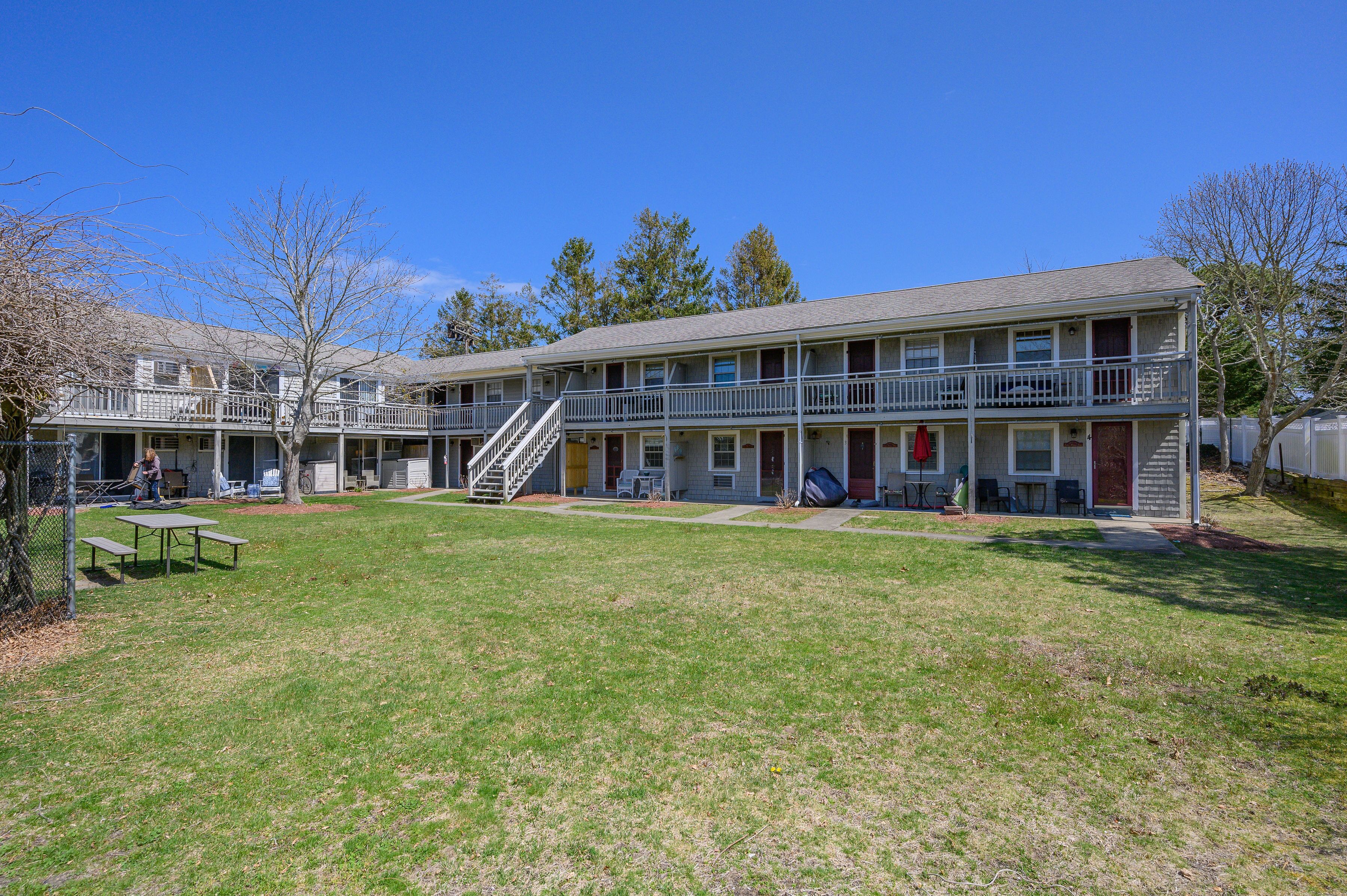 A two-story motel with a central courtyard, outdoor seating, and a staircase leading to the upper floor.