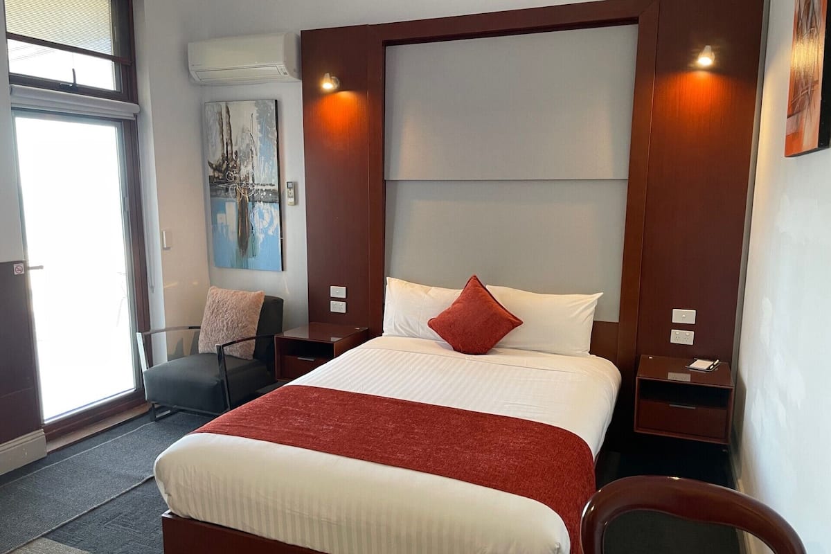Une chambre d’hôtel avec un grand lit, une chaise, un bureau et un tableau au mur.