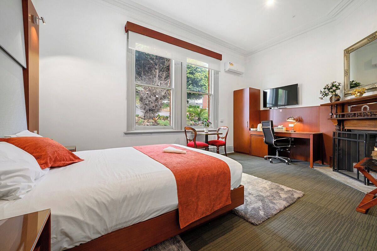 Une chambre d’hôtel avec un lit, un bureau, une chaise, une télévision et une grande fenêtre.