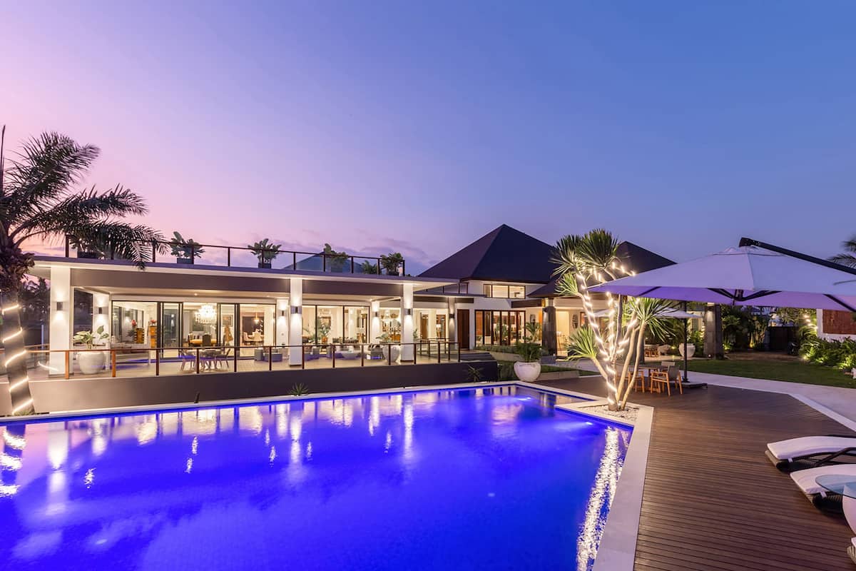 A modern hotel with a swimming pool, outdoor seating, and a well-lit patio area.