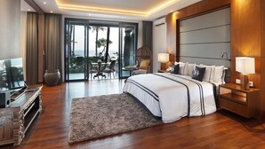 Una habitación de hotel moderna con una cama grande, un escritorio y vistas al océano a través de ventanales del piso al techo.