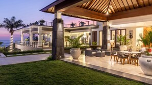 Una casa moderna con un porche cubierto, mobiliario exterior y vista al océano.