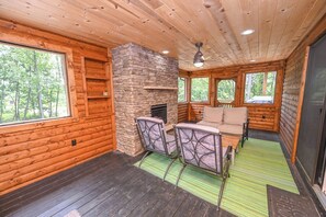A log cabin interior with a stone fireplace, wooden walls, and a green mat.