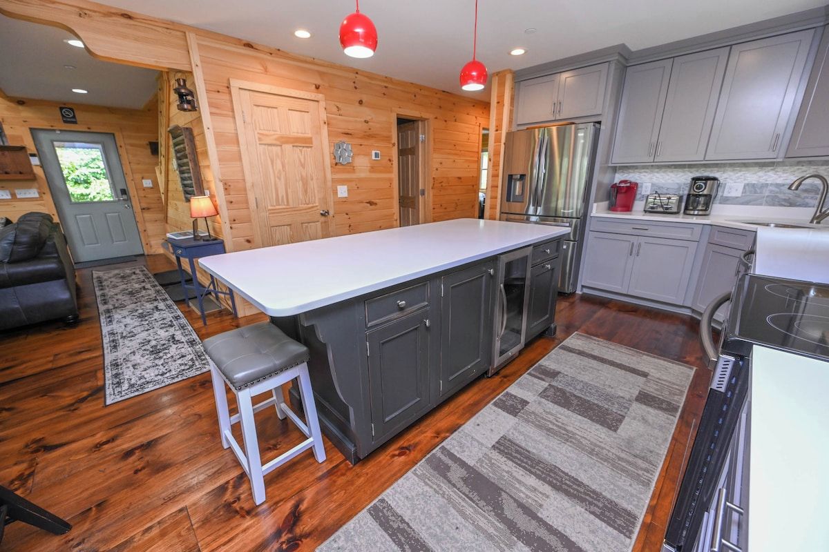 A modern kitchen with a central island, grey cabinets, and stainless steel appliances.