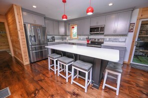 A modern kitchen with a central island, stainless steel appliances, and bar stools. - Top-of-Wisp*6bed/6ba*Hottub* (McHenry)