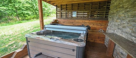 Un jacuzzi con terraza de madera y pared de piedra.