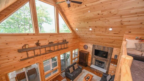 A spacious cabin with a loft bedroom, a fireplace, and large windows offering a view of the outdoors. - Top-of-Wisp*6bed/6ba*Hottub* (McHenry)