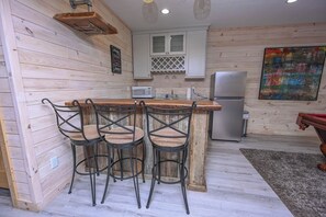 A kitchen with a wooden island, white cabinets, a microwave, and a refrigerator.