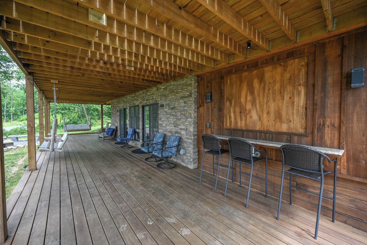 A covered outdoor area with a wooden deck, stone wall, and bar seating.