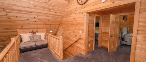 Un interior de madera con un sofá, una rueda de madera y suelo alfombrado.