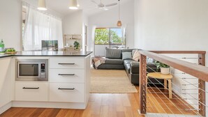 A modern kitchen with a microwave, white cabinets, and a wooden dining table. - Oasis Lennox Head unit (Lennox Head)