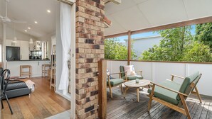 A modern kitchen with a flat-screen TV, wooden cabinets, and a dining area with a table and chairs. - Oasis Lennox Head unit (Lennox Head)