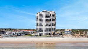 Un hotel alto de varios pisos con balcones, situado cerca de una playa.