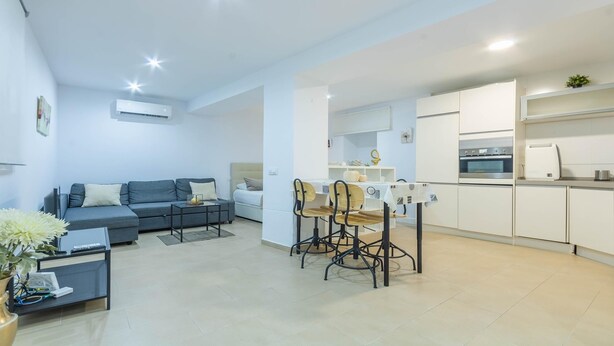 A modern apartment with a living room, dining area, and kitchen.