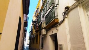 A narrow alleyway between buildings with balconies and air conditioning units.