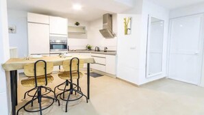 A modern kitchen with a dining area, white cabinetry, and a built-in oven.