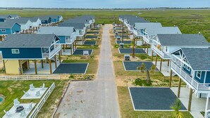 A row of beach houses with balconies, a sandy path leading to the beach, and a clear view of the ocean. - Steps to Beach & Community Pool! (Bolivar Peninsula)