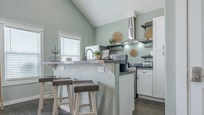 A kitchen with a central island, bar stools, a built-in oven, and a stainless steel range hood. - Steps to Beach & Community Pool! (Bolivar Peninsula)