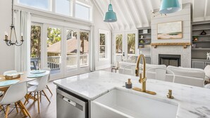 A bright kitchen with a large island, white cabinetry, and a view of the outdoors.