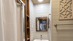 Un baño pequeño con un lavamanos blanco, tocador de madera y un espejo encima.