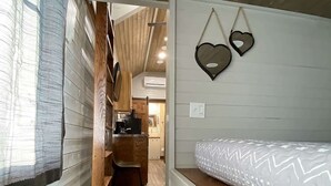 Una habitación pequeña con paneles de madera, una cama litera, un kitchenette y una decoración con forma de corazón en la pared.