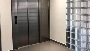 Un ascensor amb un panell digital, un detector d'incendis i un sòl de rajoles.