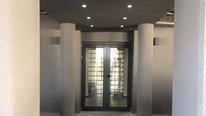 Un passadís amb una porta doble, columnes i un paviment de rajoles.