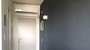 Un passadís amb una paret fosca, una porta de color clar i una petita prestatgeria de fusta.