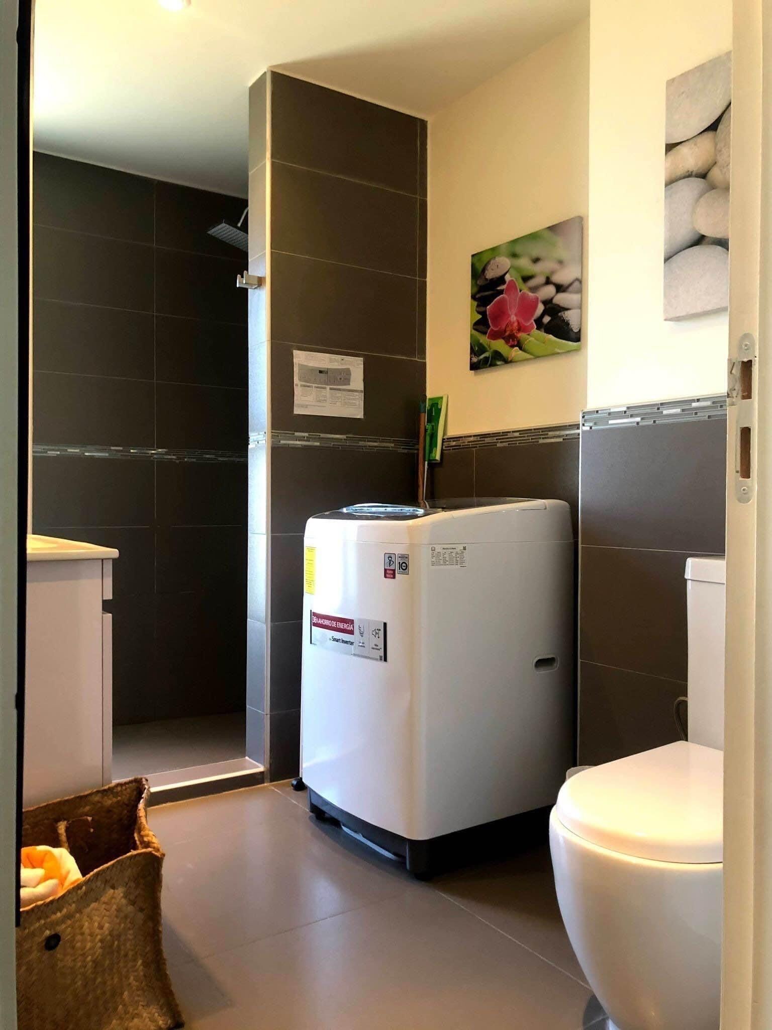 A modern bathroom with a white toilet, a white sink, and a shower area.