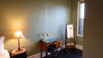 A room with a desk, chair, lamp, and mirror.