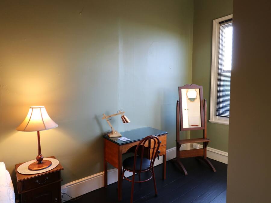 A room with a desk, chair, lamp, and mirror.