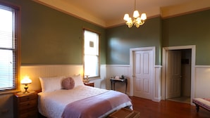 A bedroom with a bed, bedside table, lamp, and a chest of drawers. - The Exchange Beaconsfield - Offering Heritage Accommodation (Beaconsfield)