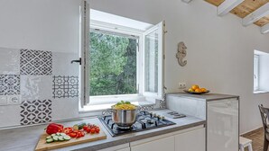 Une cuisine avec une fenêtre, un fourneau et une planche à découper avec des légumes.