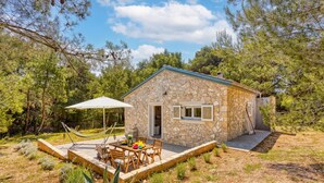 Une maison en pierre avec un patio, du mobilier d’extérieur et un hamac.