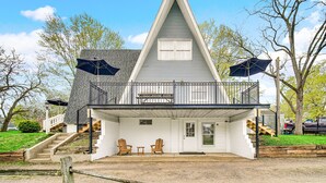 Et toetagers hus med balkon, en veranda med to stole og en trappe op til øverste etage.