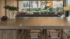 A modern kitchen with a large island, seating area, and large windows offering a view of the outdoors. - Veyla Natai Residence - Luxury Pool Villa  (Takua Thung)