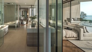 A modern interior with a glass-enclosed bathroom, a seating area with a view of the ocean, and a minimalist design. - Veyla Natai Residence - Luxury Pool Villa  (Takua Thung)