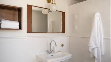 A bathroom with a white sink, a mirror, and a towel hanging on the wall.