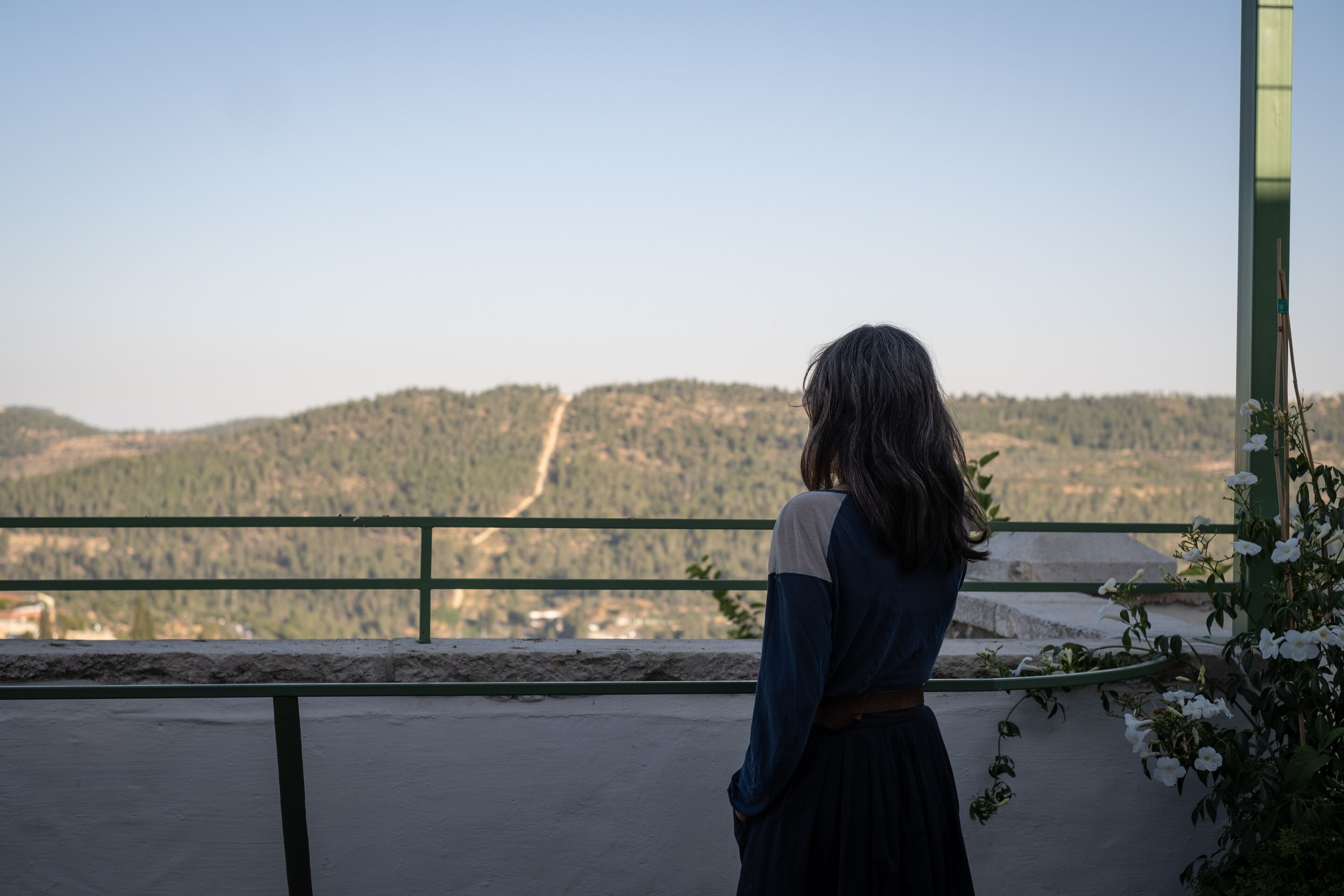 A person standing on a balcony overlooking a mountainous landscape.