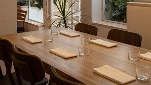 A dining area with a long wooden table, chairs, and a modern pendant light. - KHAN EIN KAREM BOUTIQUE HOTEL (Jerusalem)