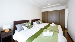 A hotel room with two beds, a nightstand with a lamp, and a wardrobe. - Dynasty Nijuyonken (Sapporo)