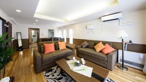 A modern living room with two sofas, a coffee table, and a dining area. - Dynasty Nijuyonken (Sapporo)