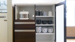 A kitchen with a built-in refrigerator, a stove, and a shelf with various kitchenware. - Dynasty Nijuyonken (Sapporo)