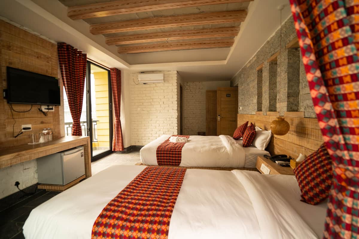 A hotel room with two beds, a desk with a television, and a small refrigerator.